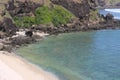 Rocks by the sea, a little greenery and sand Royalty Free Stock Photo