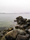 Rocks in the sea at stanley park seawall in vancouver with cargo ships at background in the fog Royalty Free Stock Photo