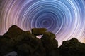 The rocks silhouette on the hill under the colorful star trails on the sky. Night timelapse photography. Royalty Free Stock Photo