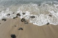 Rocks and small waves breaking on sandy beach Royalty Free Stock Photo