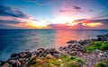 Rocks on stone beach at sunset. Beautiful landscape of calm sea. Tropical sea at dusk. Dramatic colorful sunset sky and cloud.