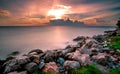 Rocks on stone beach at sunset. Beautiful landscape of calm sea. Tropical sea at dusk. Dramatic golden sunset sky and clouds.