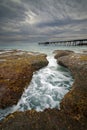 rocks and water leading out to a wharf at catherine hill bay in australia Royalty Free Stock Photo
