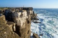 Rocks and waves of surf in the ocean near Cabo Carvoeiro, Peniche peninsula with Lighthouse on background, Portugal Royalty Free Stock Photo