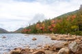 Rocks wrap around the shore of Jordan Pond leading to a forest of pine trees and colorful maples Royalty Free Stock Photo