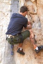 Rockstar of rock climbing. Rearview of a tattooed rock climber clinging onto a crack in the rockface. Royalty Free Stock Photo