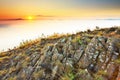 Rocky basalt peak on hill. Forest valley full of gentle fog and Sun above heavy mist. Royalty Free Stock Photo