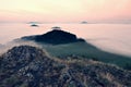 Rocky basalt peak on hill. Forest valley full of gentle fog and Sun above heavy mist. Royalty Free Stock Photo