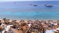 Rocky beach with Arabic cafes in retro style on the red sea coast with umbrellas, sun beds and corals. Egypt