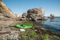 Rocky beach and kayak, overlooking Pacific ocean and rocky cliffs with flock of birds