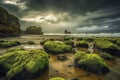 A rocky beach with moss-covered rocks under a dramatic sky with rays of sunlight shining through the dark clouds Royalty Free Stock Photo