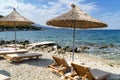 Rocky beach in Ksamil, Ionian Sea with sunbeds and straw umbrellas. Blue and tourquse sea in background, nobody. Royalty Free Stock Photo