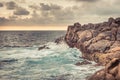 Rocky beach with stormy ocean and sunset sky as tropical landscape in Sri Lanka