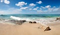 Rocky beach view at Caribbean sea coast, with light blue sky, turquoise water and white clouds. Sunny beach landscape with rocks