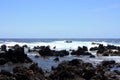 Rocky, black lava rock shoreline fronting deep blue Pacific Ocean at Laupahoehoe Point in Hawaii