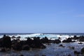 Rocky, black lava shoreline fronting deep blue Pacific Ocean at Laupahoehoe Point with clear blue skies