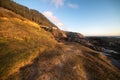 Rocky cliff and green grass at ocean beach at sunset time Royalty Free Stock Photo