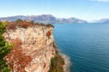 Rocky cliff of Lake Garda and a view of the Alps surrounding the lake Royalty Free Stock Photo