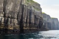 A rocky cliff with a small boat in the water