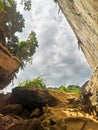 Rocky cliff with sunlight coming through, a cave with rocks and stones