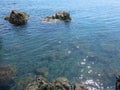 Rocky cliffs of abstract shapes protrude above the surface. Crystal clear sea water. Coral subsoil underwater. Azure blue sea.