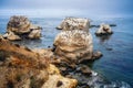 Rocky cliffs at low tide, flock of birds, and dark blue ocean. Overcast day at Pismo Beach, California Royalty Free Stock Photo
