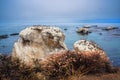 Rocky cliffs at low tide, flock of birds, and dark blue ocean. Overcast day at Pismo Beach, California Royalty Free Stock Photo