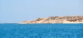 Rocky coast on the sea against background of a blue cloudless sky. Beautiful Egyptian landscape