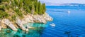 Rocky coastline covered by cypress and tourest boats in azure water, near Kalami, Corfu Royalty Free Stock Photo