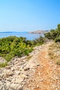 Rocky coastline with a foot path and bushes and trees by the Adr