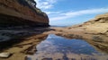 Rocky coastline with layered cliffs and a tidal pool in the foreground, reflecting the blue sky and clouds Royalty Free Stock Photo