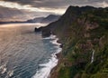 Rocky coastline of Madeira with waterfalls, wave and sunset