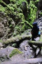 A rocky crevice covered with moss and a girl in a black hood