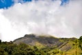 Rocky green hill covered by clouds