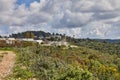 Rocky hill with a dirt road in front under a blue sky with white clouds and a modern villa on top Royalty Free Stock Photo