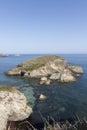 a rocky island covered in greenery, surrounded by clear blue water under a bright blue sky Royalty Free Stock Photo