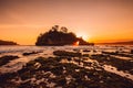 Rocky island in ocean and bright sunset at beach Royalty Free Stock Photo