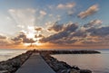 Rocky jetty / pier at sunrise with dramatic cloudy sky and smooth sea, cala bona, mallorca, spain Royalty Free Stock Photo