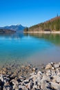 Rocky lake shore Walchensee in march, boathouse and alps view Jachenau