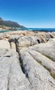 Rocky landscape leading to the sea under cloudy blue sky copy space at Camps Bay beach, Cape Town, South Africa Royalty Free Stock Photo