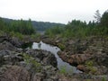 A rocky landscape with trees and rocks in the foreground. Suna River, Poor Porog Waterfall, Girvas