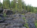 A rocky landscape with trees and rocks in the foreground. Waterfall Poor Porog, Girvas