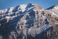 Rocky mountain with layered sharp slopes and snow on them and cliffs made of stones Royalty Free Stock Photo