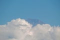 Rocky mountain peak emerging above thick white clouds against a vast blue sky Royalty Free Stock Photo