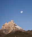 Rocky mountain peaks with the remains of snow against the background of a blue morning sky with a saturated moon Royalty Free Stock Photo