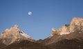 Rocky mountain peaks with the remains of snow against the background of a blue morning sky with a saturated moon Royalty Free Stock Photo