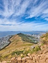 Rocky mountain with view of a costal city by the sea in Cape Town. Landscape of green hill top with stones and plants