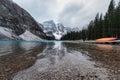 Rocky mountains with canoe on pier in Moraine Lake on gloomy at Banff national park Royalty Free Stock Photo