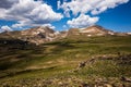 The Rocky Mountains with green grassy foreground against blue sky and white clouds Royalty Free Stock Photo