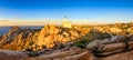 Rocky ocean coastline panorama with lighthouse at sunset Royalty Free Stock Photo